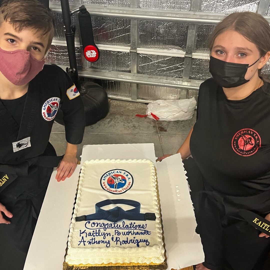 Two people standing next to a cake on top of a table.